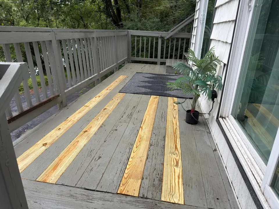 Replacement wood boards installed on a small gray deck