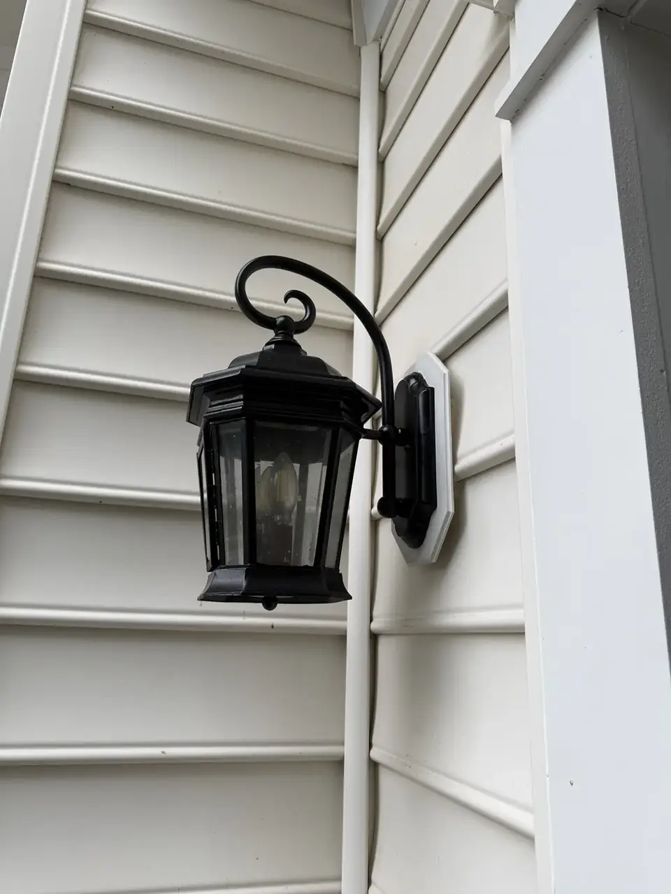 Replacement black exterior lantern fitted against the home siding