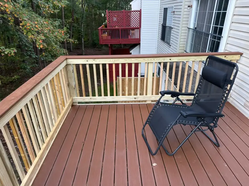 Finished deck surface with wood railing and a lounge chair