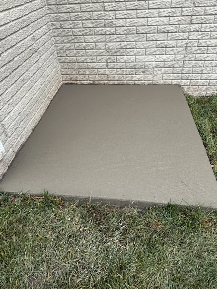 Rectangular concrete pad beside the home's brick exterior