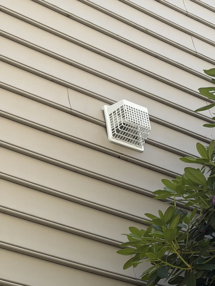White exterior vent cover fitted to the home's siding
