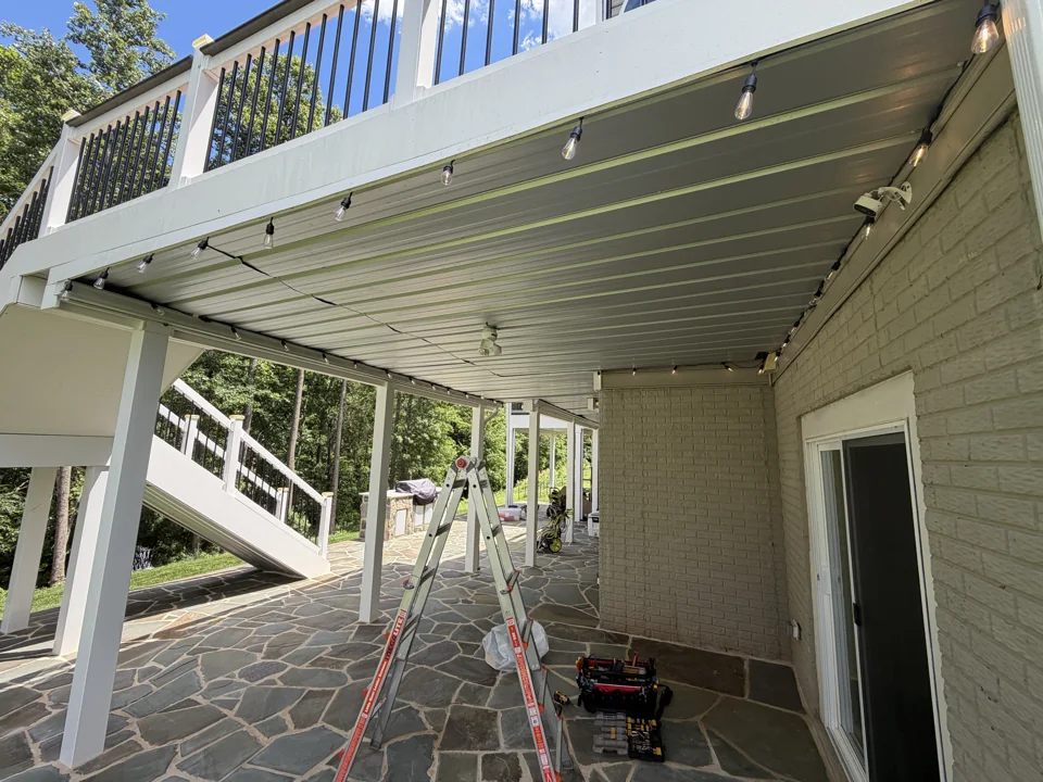 Under-deck ceiling installation with a ladder and tools in the work area